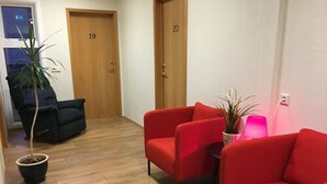 A hallway with two doors, numbered 19 and 20, and a seating area with red chairs and a small table. - Framtid Hostel (Djupivogur)