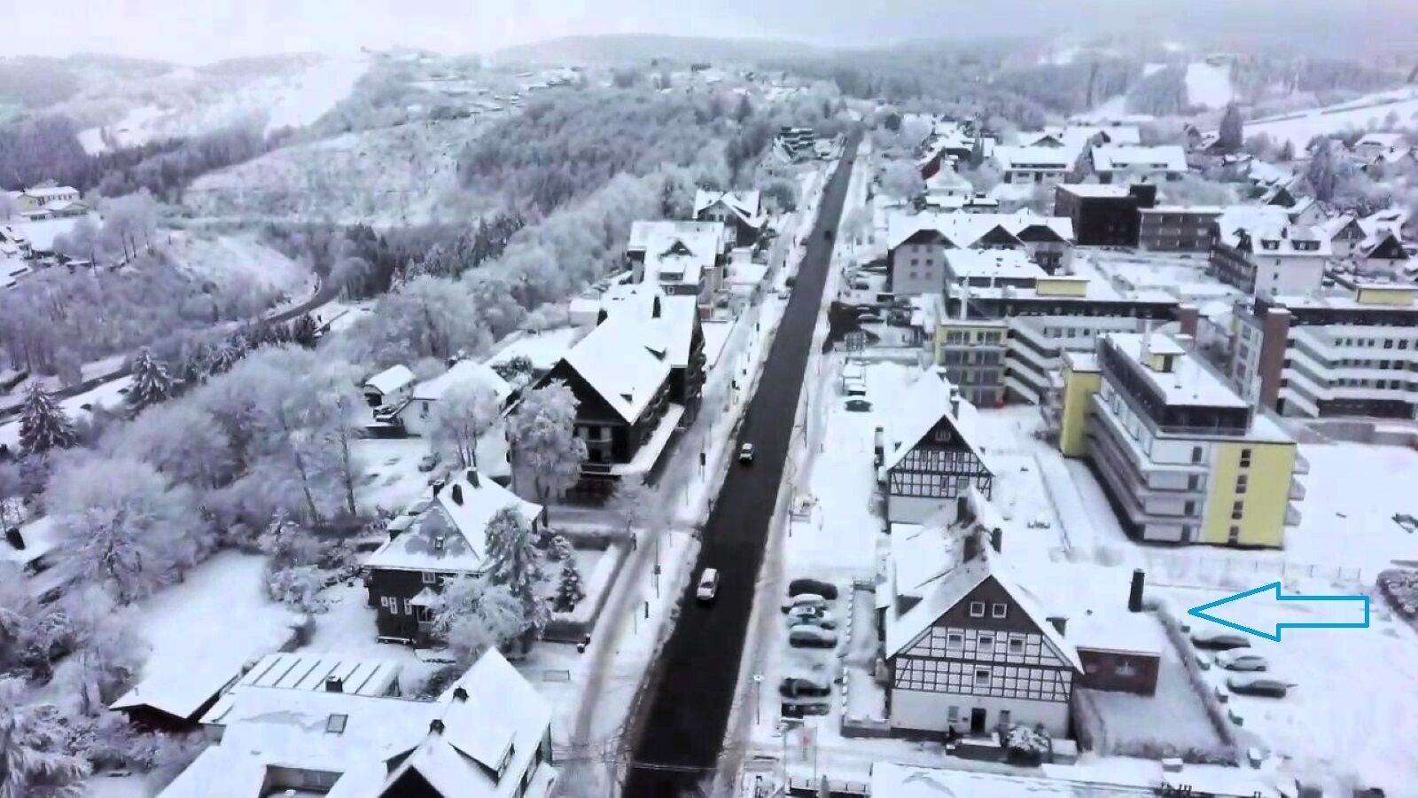 An aerial view of a snow-covered town with buildings, roads, and vehicles.