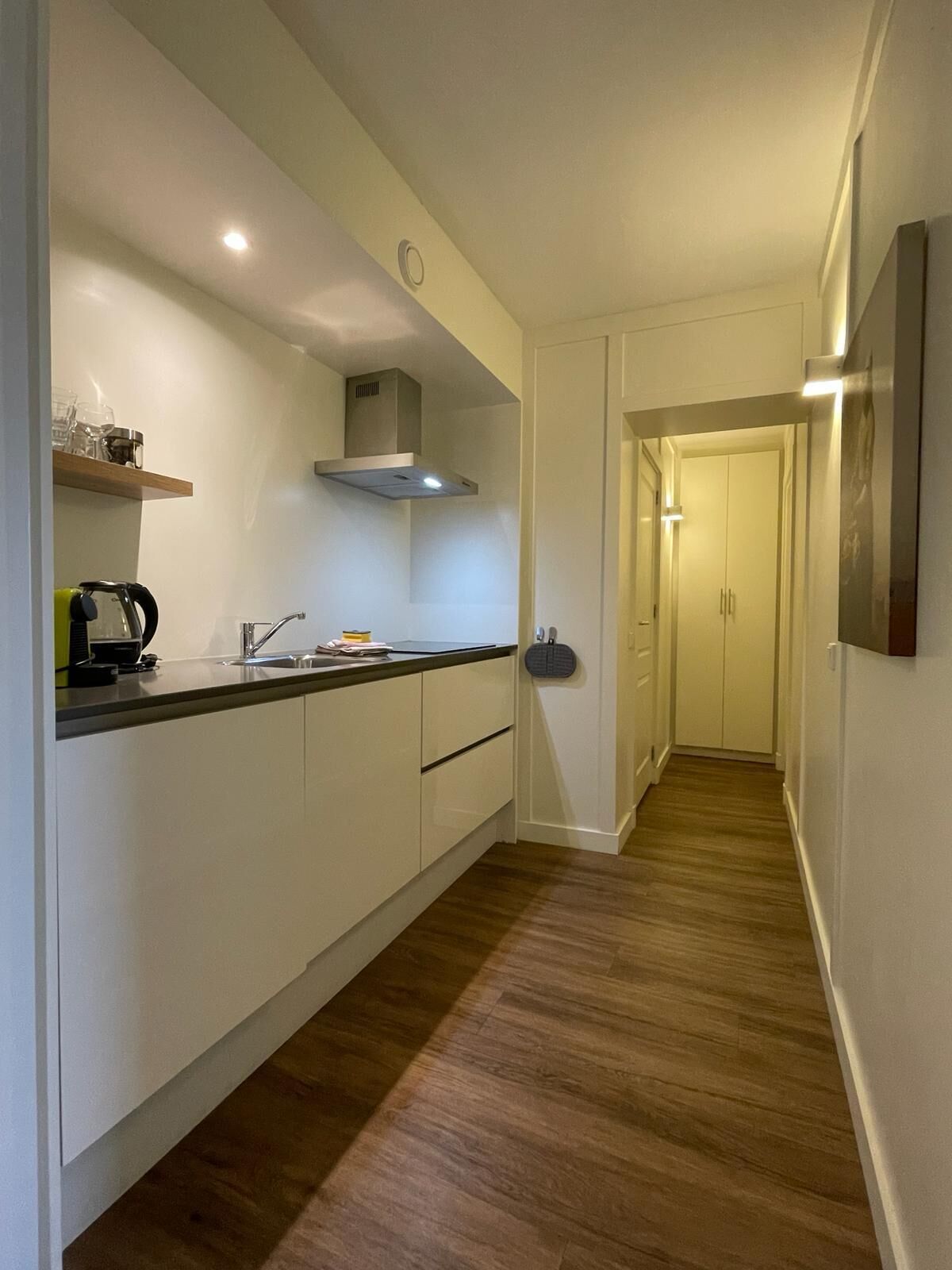 A modern kitchen with white cabinets, a stainless steel range hood, and a wooden countertop.