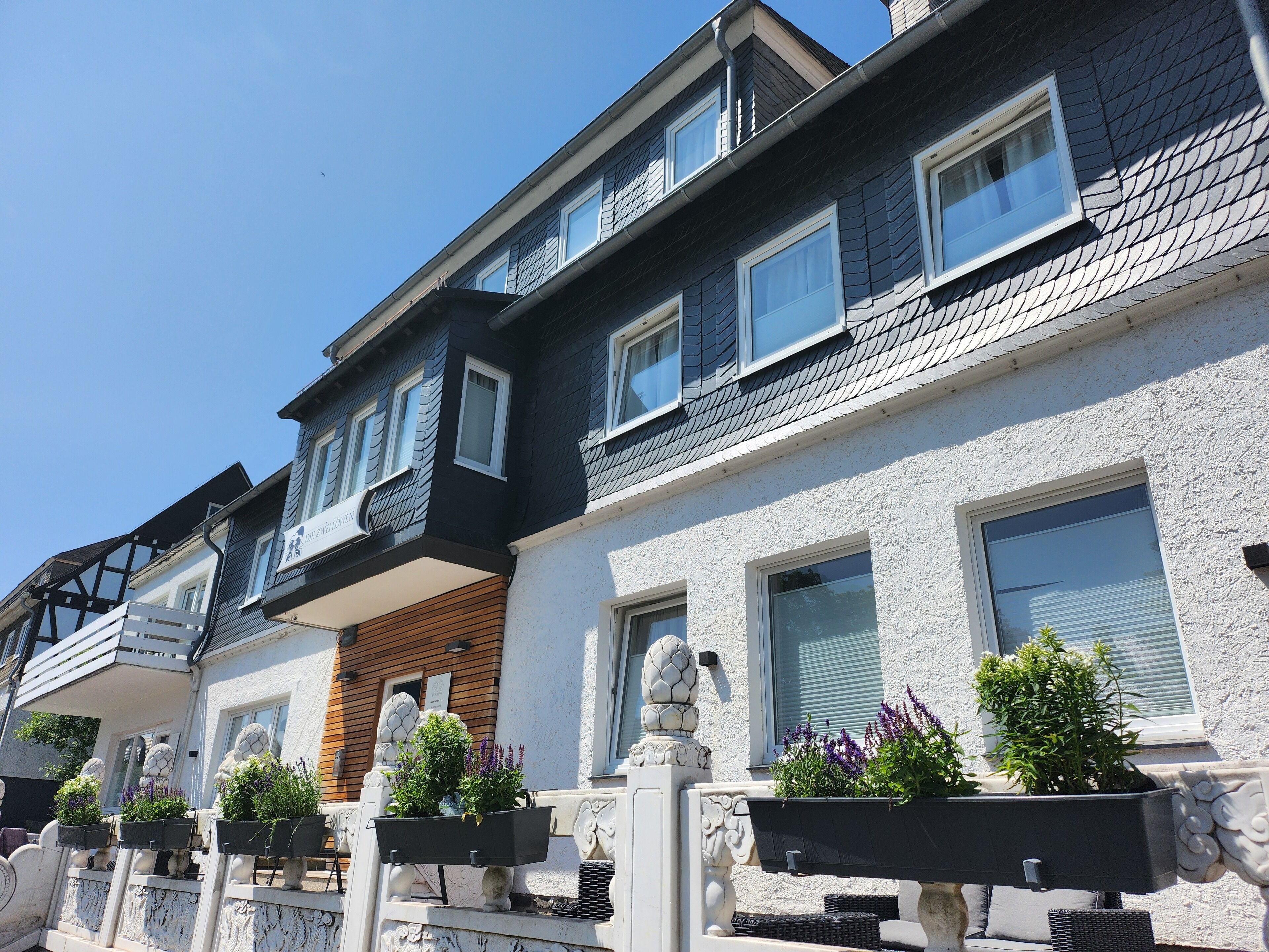 Una hilera de casas adosadas con varias ventanas, balcones y jardineras exteriores con flores.