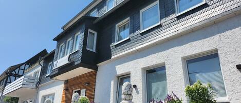 Una hilera de casas adosadas con varias ventanas, balcones y jardineras exteriores con flores.