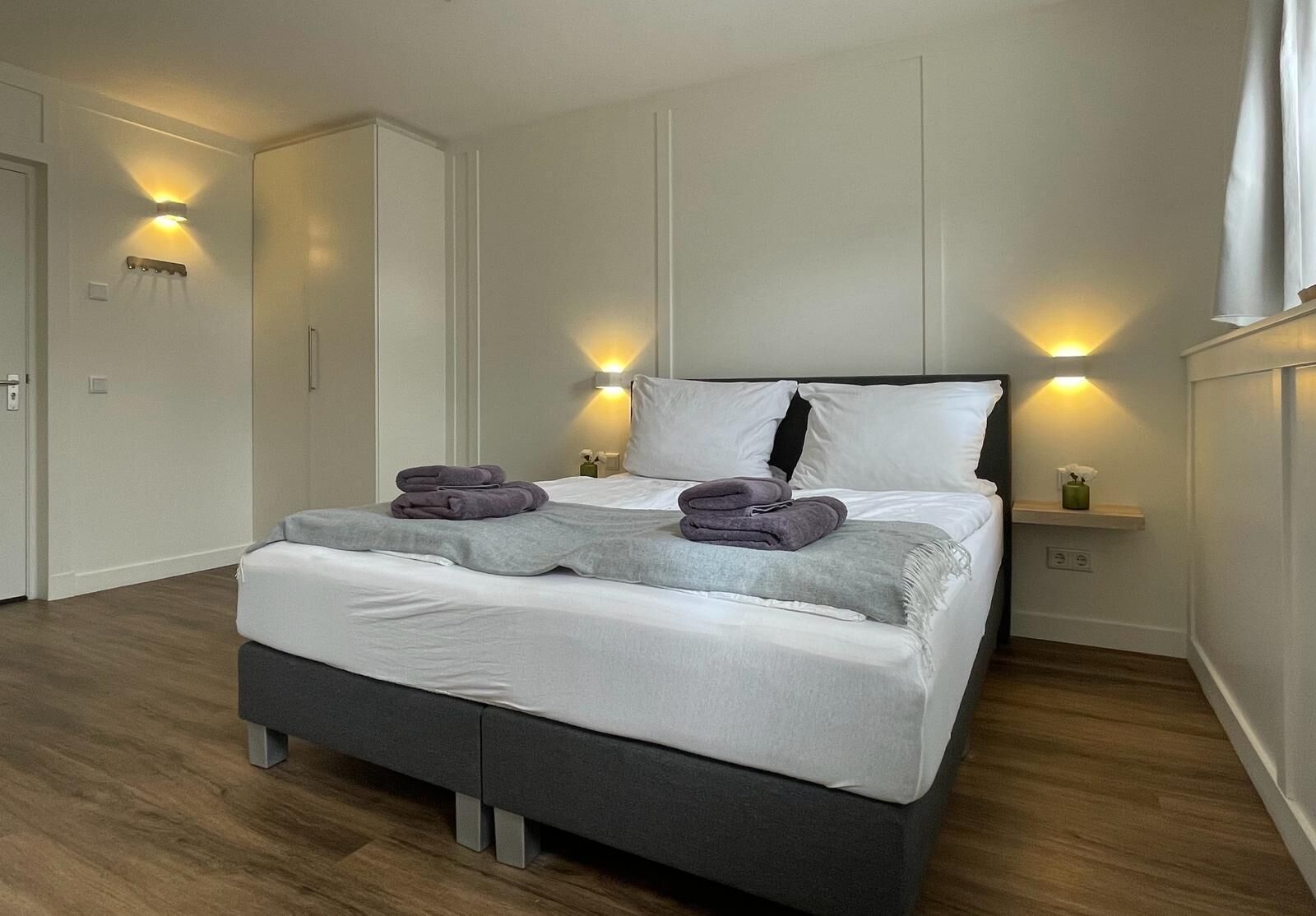 Un dormitorio moderno con una cama grande, dos mesitas de noche y armarios empotrados.
