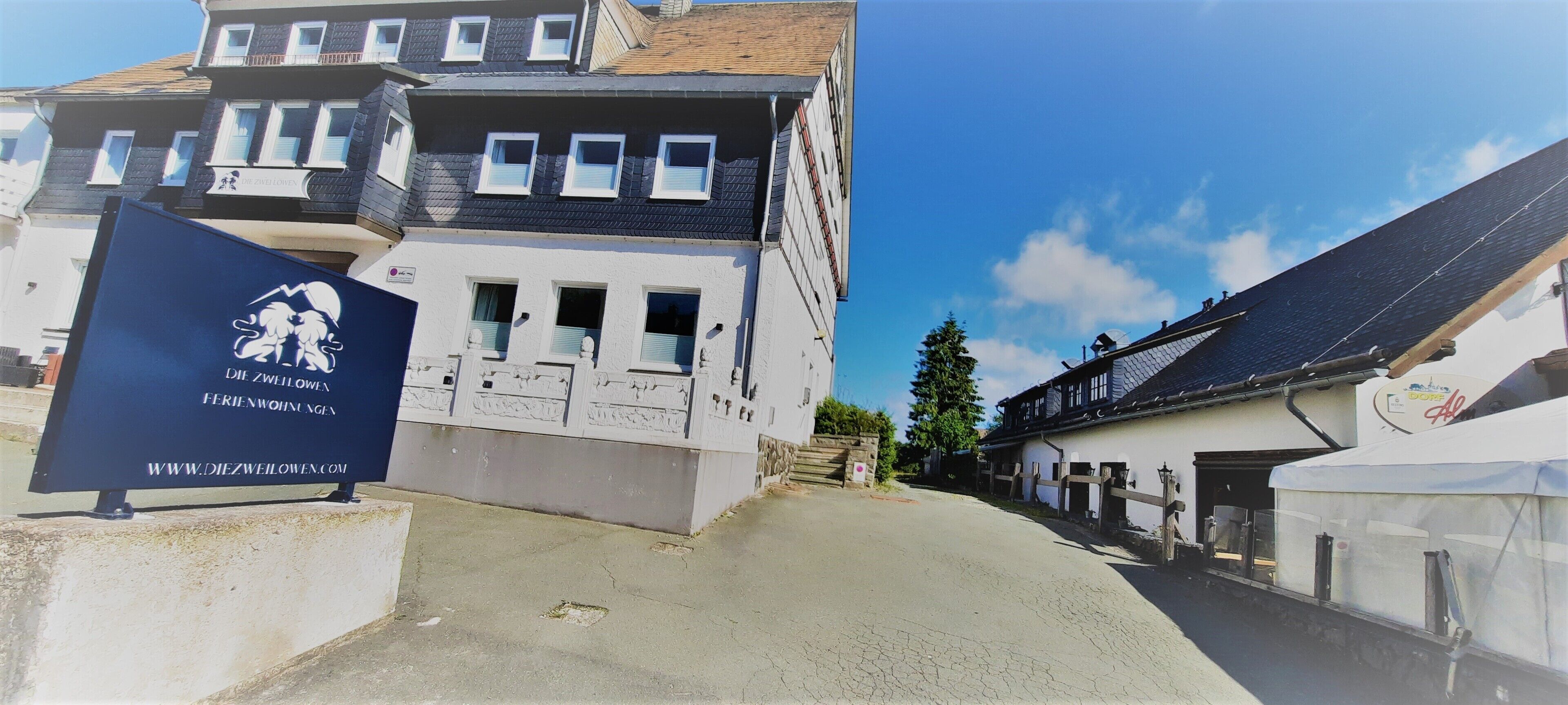 Un bâtiment portant une enseigne avec l’inscription « Die Zwillinge » et une adresse de site web.