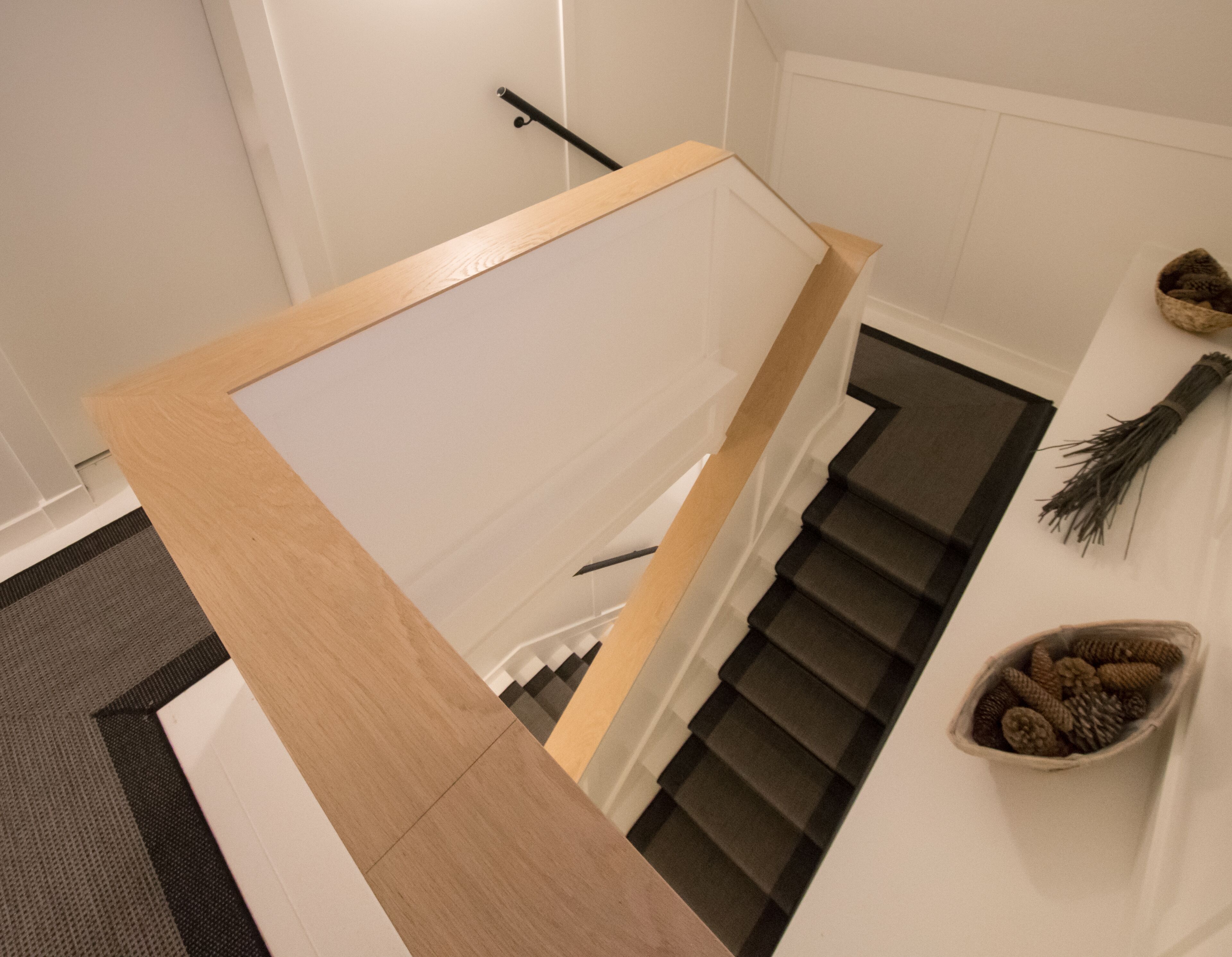 A modern staircase with a wooden handrail and a carpeted landing.