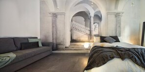 Una sala de estar moderna con un sofá, una cama y una escalera que sube a un nivel superior.