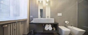 Modern bathroom with a large mirror, shelf, and separate toilet area.