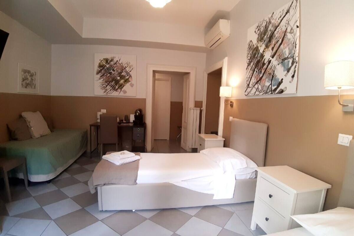 Une chambre d’hôtel comprenant un lit, un bureau, une chaise, une table de chevet et des œuvres d’art accrochées aux murs.