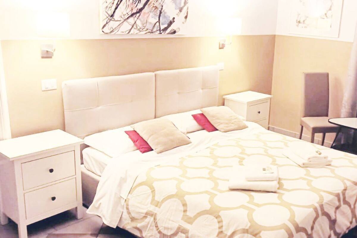 Une chambre d’hôtel comprenant un lit, deux tables de chevet, une chaise et une petite table.