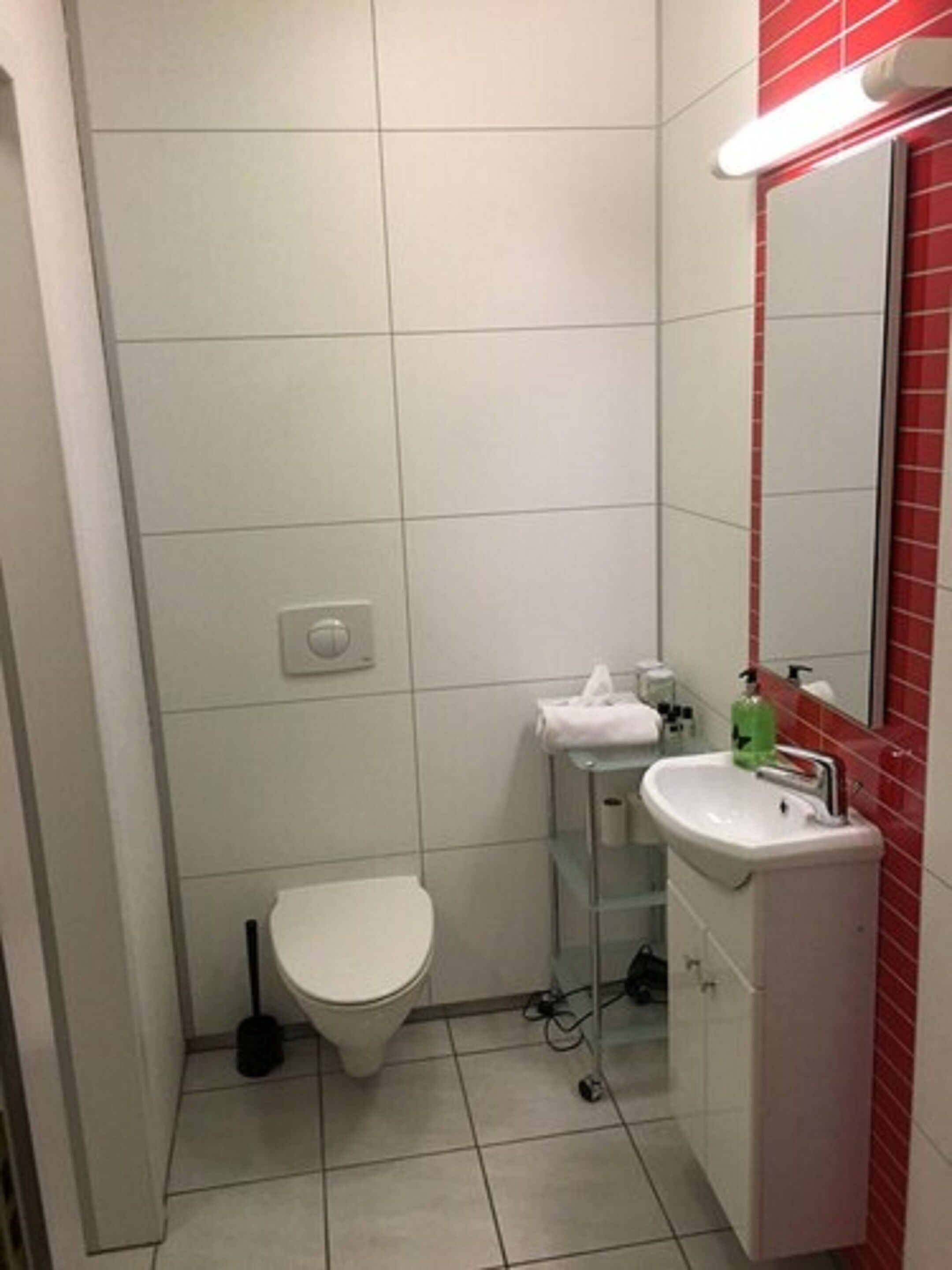 A small, clean bathroom with a toilet, sink, and mirror.
