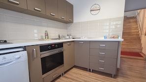 A compact kitchen with a dishwasher, oven, and a sink.