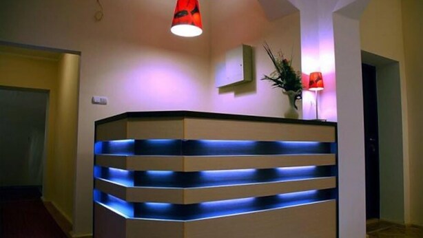 Un mostrador de recepción de diseño moderno, con iluminación azul en la parte inferior y una lámpara colgante roja.
