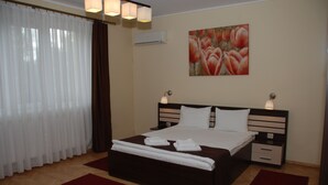 Habitación de hotel con una cama grande, dos mesitas de noche, aire acondicionado de pared y un cuadro sobre la cama.