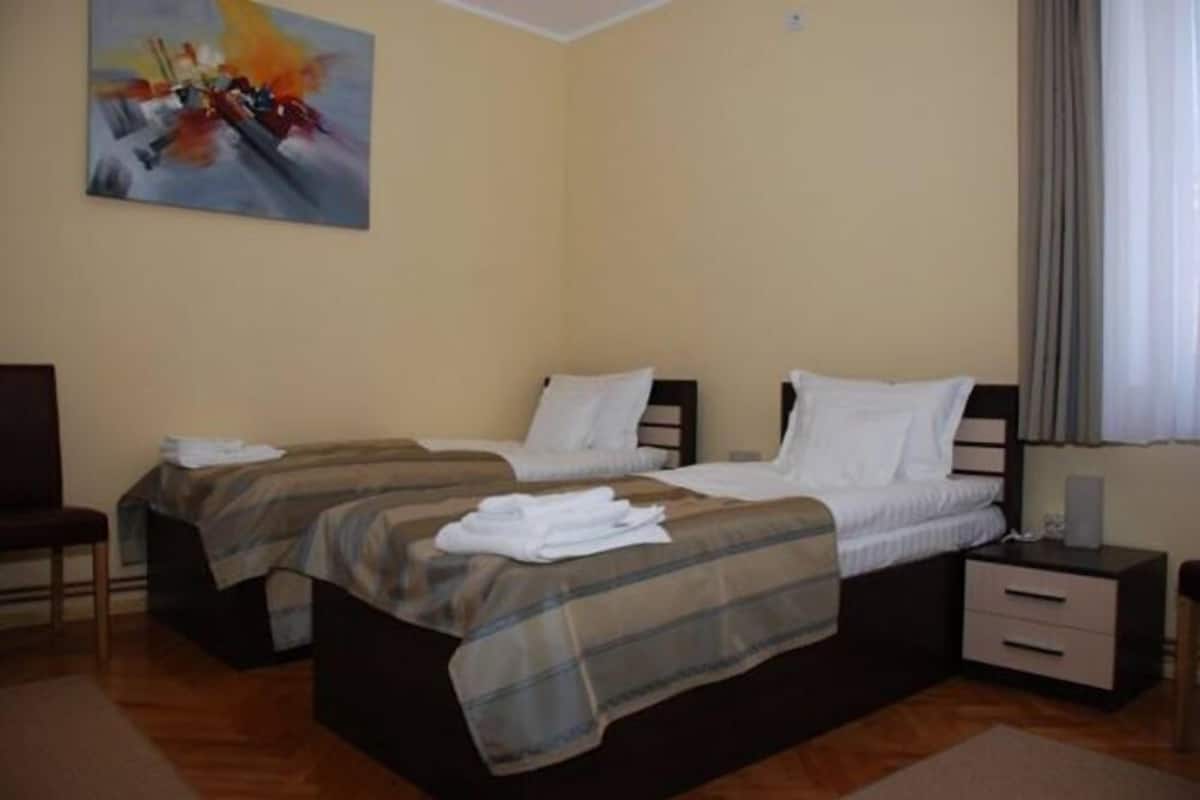 Une chambre double avec deux lits, une chaise, une table de chevet et un tableau au mur.
