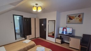 A hotel room with a bed, a television, a desk, and a mirror.