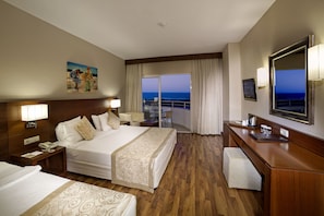 A hotel room with a bed, bedside table, lamp, and a view of the ocean.