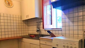 Eine Küche mit weißen Schränken, einem Herd und einem Fenster mit Blick auf Bäume.