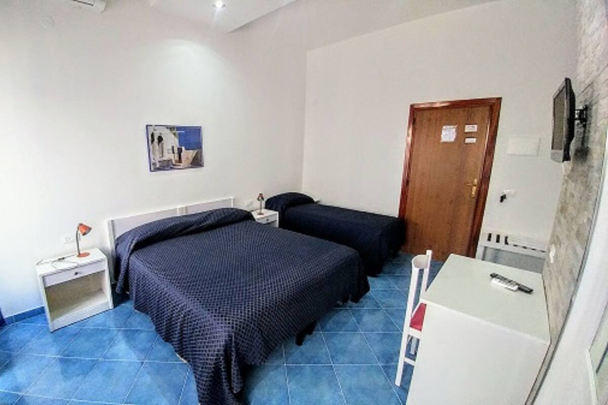 A bedroom with two beds, a desk, a chair, and a TV.