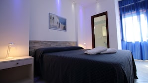 Ein Schlafzimmer mit Bett, Nachttisch, einem an der Wand hängenden Bild und einem Fenster mit Vorhängen.