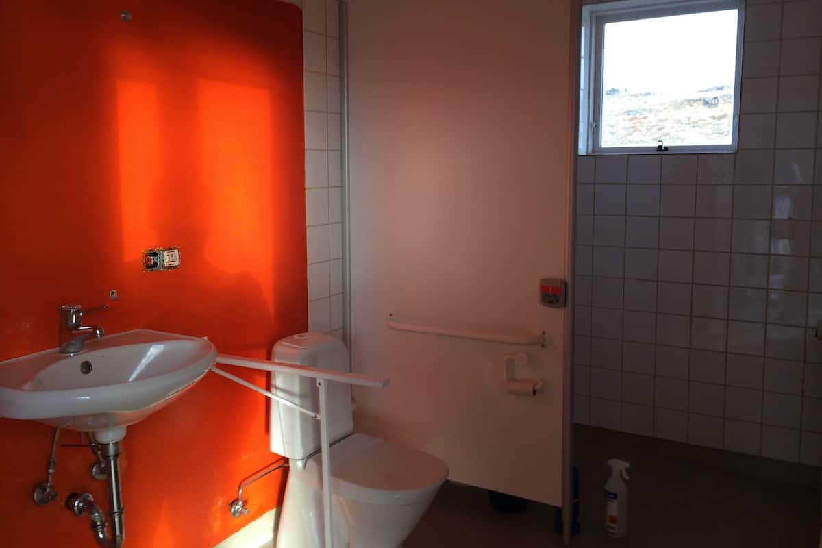 Ein Badezimmer mit roter Wand, weißem Waschbecken und Toilette.