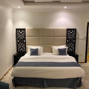 Ein modernes Schlafzimmer mit einem großen Bett, zwei Nachttischen und dekorativen Wandverzierungen.