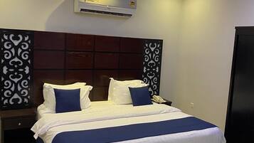 Una habitación de hotel moderna con una cama grande, una mesita de noche, un teléfono y un aire acondicionado instalado en la pared.