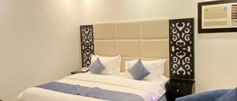 A neatly arranged bedroom with a large bed, a bedside table, a chair, and decorative wall panels.