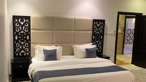 Une chambre à coucher bien aménagée, avec un grand lit, deux tables de chevet et un panneau décoratif au mur.