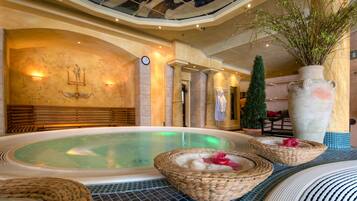 Ein luxuriöser Innenpoolbereich mit großzügigem Whirlpool, Korbwannen und einer dekorativen Vase.
