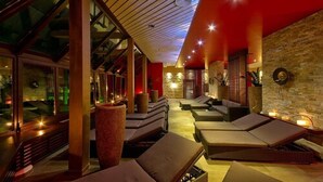 A spa area with sun loungers, a large window, and a stone wall. - Vital Hotel Westfalen Therme (Bad Lippspringe)