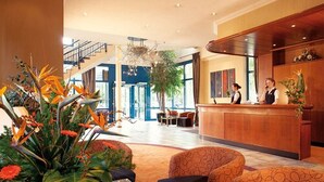 A hotel lobby with a reception desk, seating area, and a staircase. - Vital Hotel Westfalen Therme (Bad Lippspringe)