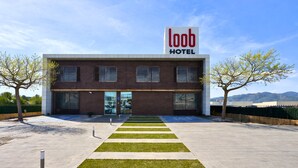 Un hotel moderno con un letrero llamativo, una entrada principal y un estacionamiento.