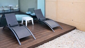 Un espacio exterior moderno con dos sillones de descanso y una pequeña mesa blanca.
