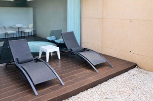 Un espacio exterior moderno con dos sillones de descanso y una pequeña mesa blanca.