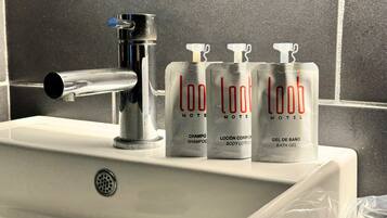 A bathroom sink with a chrome faucet and three bottles of 'loo hotel' branded toiletries.