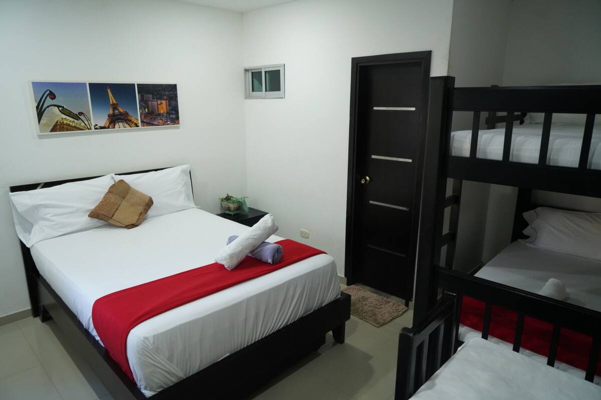 A room with a single bed, a nightstand, a small window, and a door.