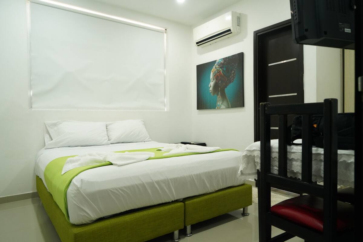 A modern hotel room with a bed, a desk, a chair, and a window.