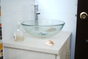 A bathroom with a glass bowl sink, a soap dispenser, and a door with a lock. - Hotel Sun River (Barranquilla)