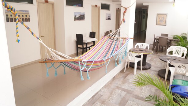A room with a hammock, a dining area with chairs, and a small table. - Hotel Sun River (Barranquilla)