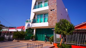 A modern building with a two-story structure, a balcony on the upper floor, and a green door. - Hotel Sun River (Barranquilla)