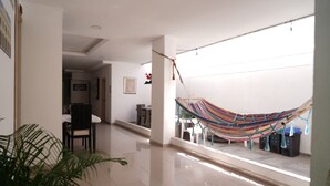 A spacious hallway with a hammock, a dining area, and a potted plant. - Hotel Sun River (Barranquilla)