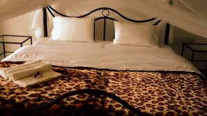 A bed with a canopy, white bedding, and a leopard print cover. - St. Eugene's Hostel (Lushoto)