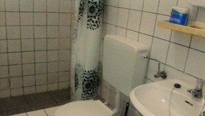 A bathroom with a toilet, sink, and shower. - St. Eugene's Hostel (Lushoto)
