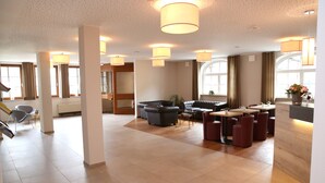 A spacious hotel lobby with a modern design, featuring a seating area with sofas and tables, a reception desk, and large windows providing natural light. - Landhotel Traube (Konstanz)
