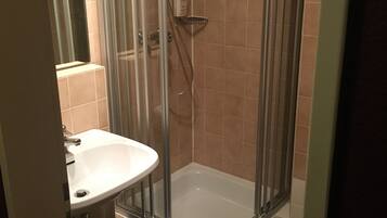 Un baño con ducha envuelta en vidrio, un lavabo blanco y un perchero para toallas.