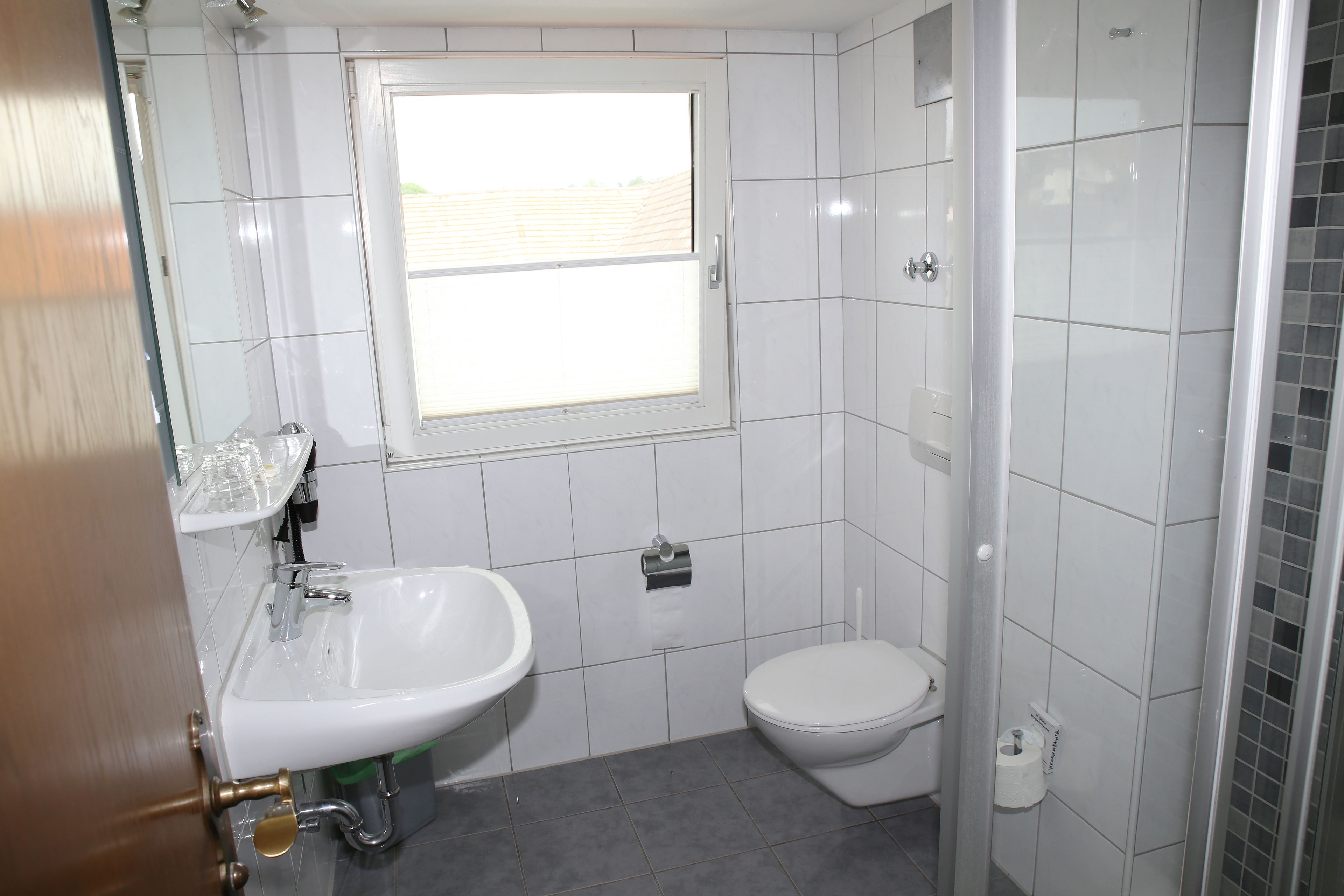 A bathroom with a white sink, toilet, and window.
