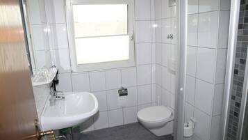 A bathroom with a white sink, toilet, and window.