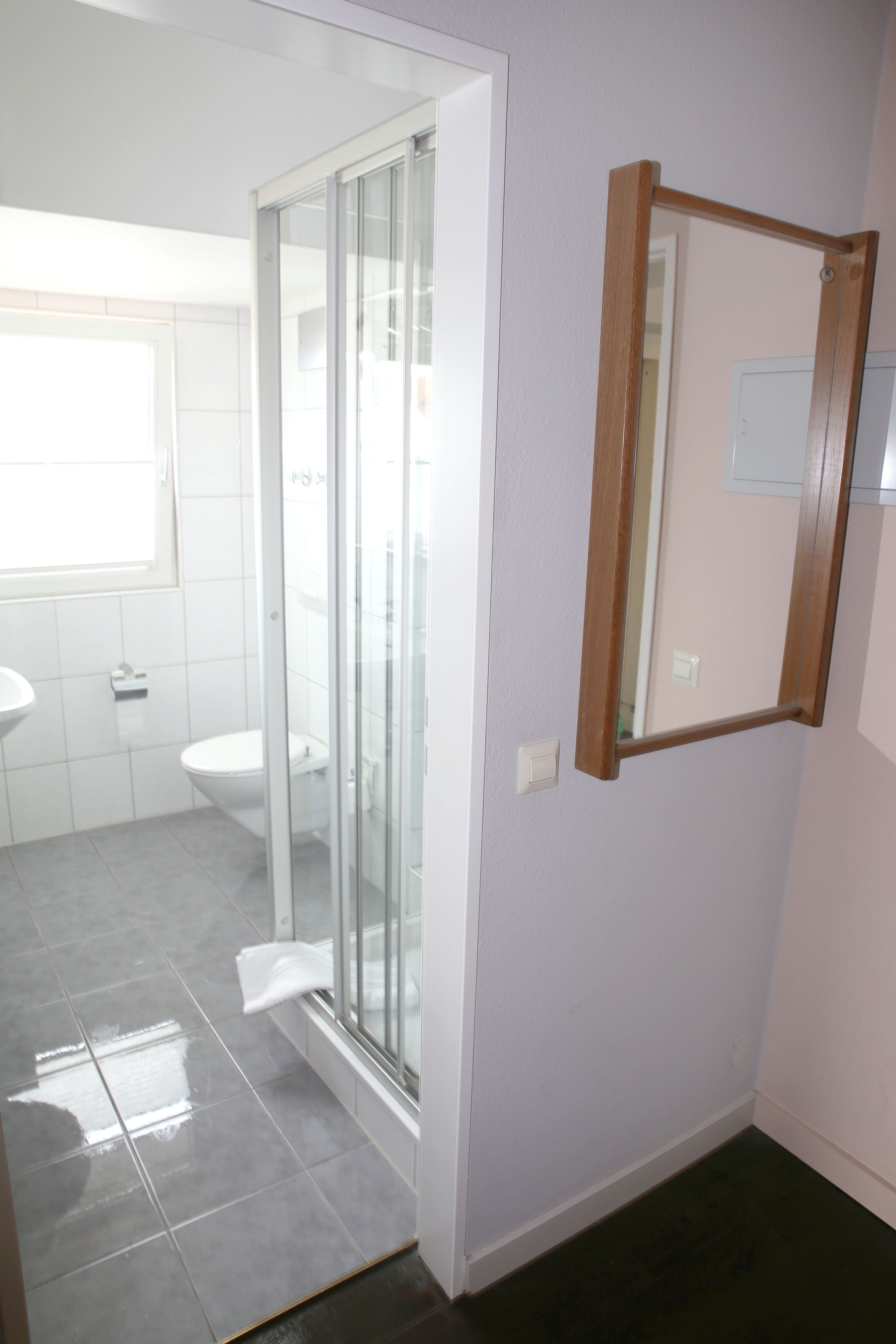 A bathroom with a glass shower enclosure, a white sink, and a mirror on the wall.