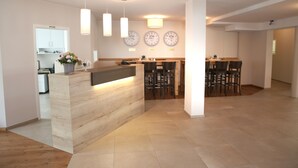 A modern kitchen with wooden countertops, pendant lights, and wall clocks. - Landhotel Traube (Konstanz)