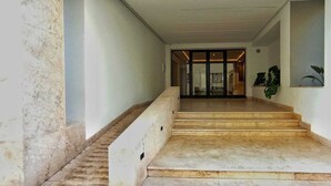 A hallway with marble steps leading to a glass door entrance.