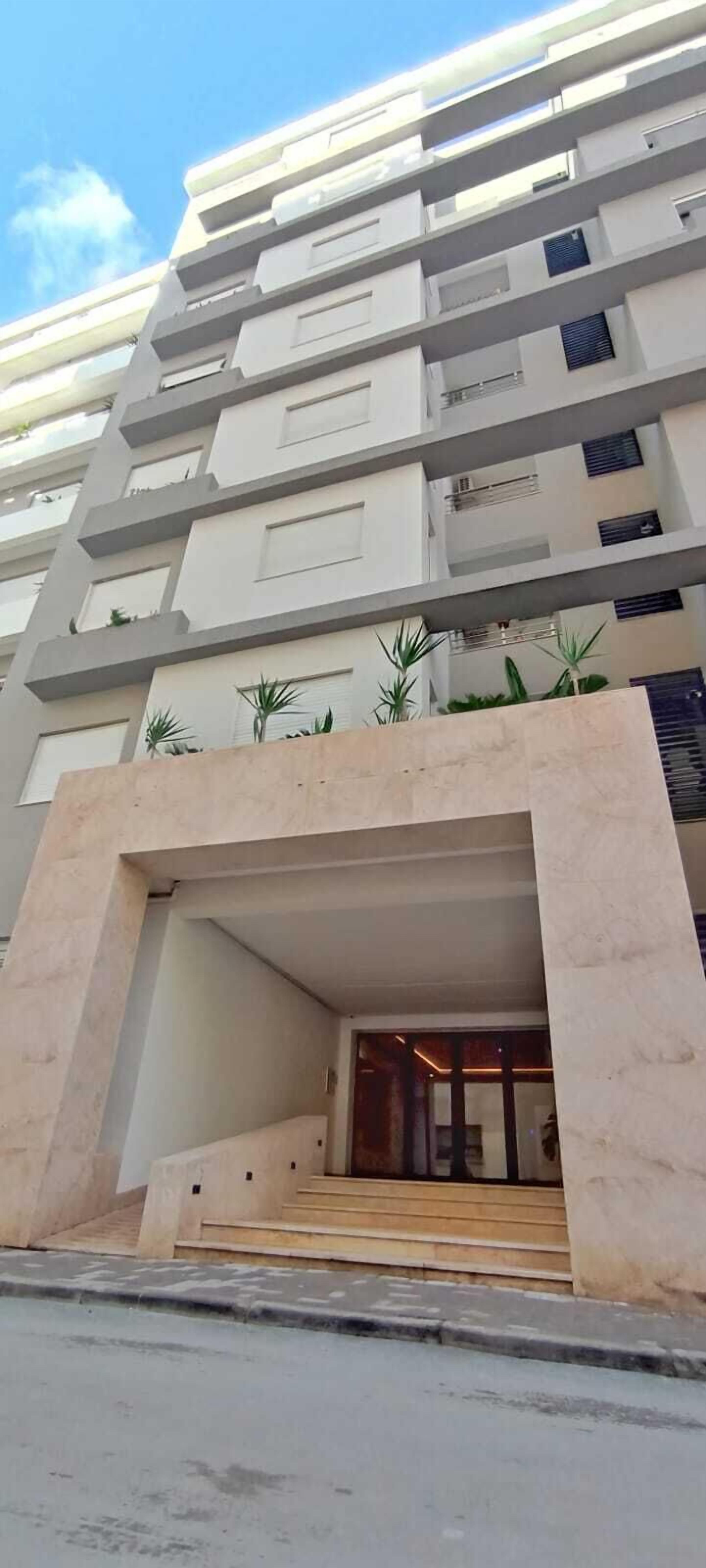 Un edificio moderno de varios pisos con una entrada central y una escalera que lleva a la planta baja.